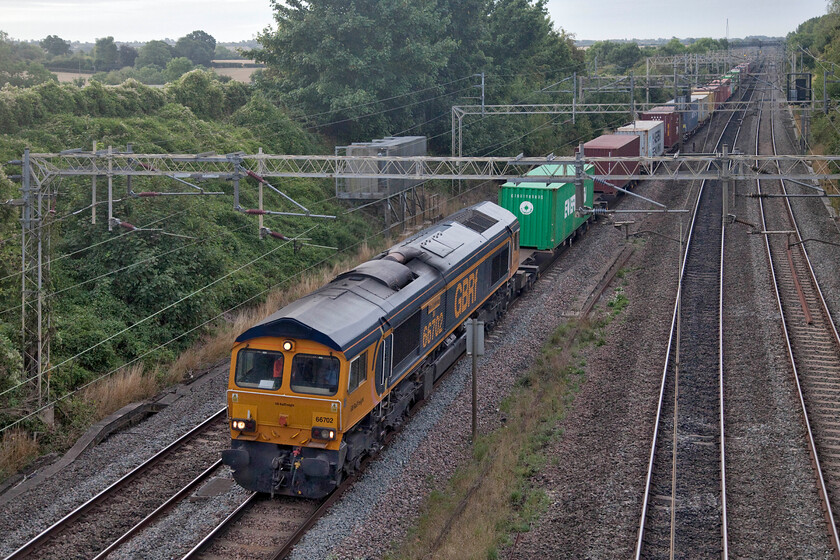 66702, 03.10 Felixstowe North-Trafford Park (4M18, 2L), Victoria bridge 
 66702 'Blue Lightening' leads the 03.10 Felixstowe to Trafford Park service past Victoria bridge between Roade and Ashton in Northamptonshire. This is one of my favourite 'go-to' local spots but a photograph from this angle at this time in the morning (just after sunrise) would normally be impossible with the sun to the left and causing a deep shadow on the track and the train; good job it went in behind some stubborn cloud then! 
 Keywords: 66702 03.10 Felixstowe North-Trafford Park 4M18 Victoria bridge GBRf Bue Lightening