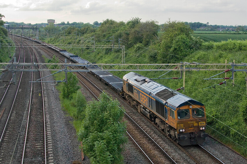 66729, 13.16 Garston Car terminal-Dagenham Docks (6L48, 40E), Victoria bridge 
 The 6L48 Garston to Dagenham Docks empty cartics rattles its way past Victoria bridge just south of Roade having run to the Merseyside car terminal the previous day loaded with new Ford products that had all been imported from mainland Europe rather than made here in the UK. This train is hauled by GBRf's 66729 'Derby County'; a relatively light load for its three thousand two hundred horse power. 
 Keywords: Derby County 66729, 13.16 Garston Car terminal-Dagenham Docks 6L48, Victoria bridge GBRf