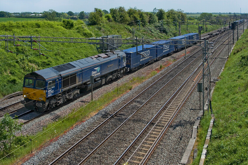 66424, 10.02 Tilbury-DIRFT (4M07, 32E), Victoria bridge 
 66424 'Driver Paul Scrivens 1969-2021' leads the daily 4M07 10.02 Tilbury to Daventry (DIRFT) Tesco Express service. On this sunny spring day, the train was noticeably shorter and lightly loaded than it normally is. Time to head for home after spending an hour or so at Vctoria bridge just south of Roade on this one of many railway strike days that have blighted 2023. I had seen various freight and other operations in my time here outnumbering passenger services. 
 Keywords: 66424 10.02 Tilbury-DIRFT 4M07 Victoria bridge DRS Direct Rail Services Tesco Express 'Driver Paul Scrivens 1969-2021'