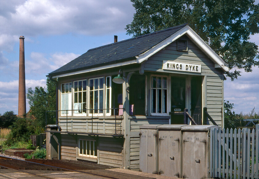 Kings Dyke signal box (GE, 1889) 
 Following our brief foray along the Lincolnshire Loop Line we headed back south around the eastern edge of Peterborough and stopped at Kings Dyke level crossing. Just west of Whittlesey the level crossing was where the busy A605 road crosses the line from Peterborough to March with Kings Dyke signal box controlling it and the associated signalling. At the time of writing in 2023 the level crossing has recently closed with the opening of the Kings Dyke Crossing Scheme which has seen a new road crossing the railway thus rendering the level crossing redundant. I was expecting the box to also have closed but when I visted in May 2023 it was still manned being the fringe box from Peterborough. The 1889 Great Eastern box is seen in happier times before it had its character denuded by a mass of UPVC, see. https://www.ontheupfast.com/p/21936chg/28569144004/kings-dyke-signal-box-great-eastern The large brickworks chimney is also now history. 
 Keywords: Kings Dyke signal box