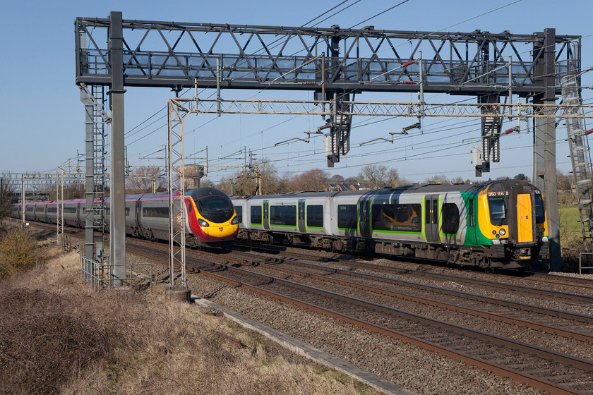 390127, VT 11.16 Manchester-London Euston (1A17, 22L) & 350106, LN 12.26 Northampton-Milton Keynes Central ECS (5K20), Roade Hill 
 All is not what it seems at Roade Hill on the WCML between Northampton and Milton Keynes. It appears that the infinitely faster Pendolino is about to overhaul the London Northwestern class 350. But, the opposite is true. 390127 'Virgin Buccaneer' is actually stationary at the red signal on the monstrosity of gantry in front whilst 350106 continues its journey as ECS to Milton Keynes with impunity. There was a severe restriction on the up fast at Milton Keynes that meant all up trains were stacked up behind each other for some distance. It took a good half an hour or so for it to sort itself out with most Virgin services arriving into Euston some twenty minutes to half an hour late. 
 Keywords: 390127 Virgin Buccaneer 1A17 350106 ECS 5K20 Roade Hill