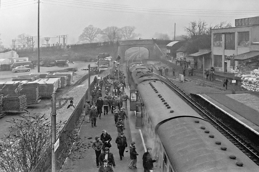 31256 & 31208, outward leg of The Crewe Campaigner Relief, 07.35 London Paddington-Crewe (1Z68), Moreton-in-Marsh station 
 Having got their pictures, the travelling enthusiast return to The Crewe Campaigner Relief at Moreton-in-Marsh station. The wood yard to the left is now home to a Budgen supermarket whilst the building to the right is still partially intact. The loading bay platform on which photographers are standing is still there if a little overgrown. 
 Keywords: 31256 31208 The Crewe Campaigner Relief 07.35 London Paddington-Crewe 1Z68 Moreton-in-Marsh station. There are a few stragglers still on the loading bay of the fertiliser distribution factory to the right. Incidentally, this building and its chimney still partially stands with the loading bay covered by undergrowth. The wood yard to the left is now the site of the town's Budgens supermarket.