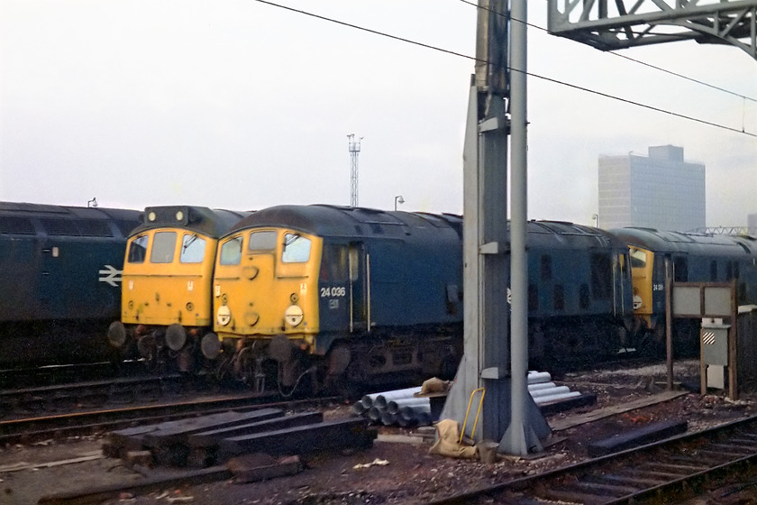 47501, 24036 & 24073, stabled, Crewe Diesel Depot 
 As we slowed down for our stop at Crewe, pictures of the Diesel Depot became slightly easier. Here 47501 is flanked by an unidentified class 25, 24036 and 24073. Both the 24s were withdrawn at this time, 24036 only a few days prior to this picture being taken. Both were taken to Doncaster and broken up. Notice the familiar sight of Rail House to the extreme right of the photograph, so noticeable as it is one of the only high-rise buildings in the area and one that is visible some distance from Crewe but heralding one's approach to the town. At the time of writing in 2022, this building still stands but has an uncertain future, see..... https://www.ontheupfast.com/p/21936chg/30029939669/rail-house-crewe 
 Keywords: 47501 24036 24073 Crewe Diesel Depot