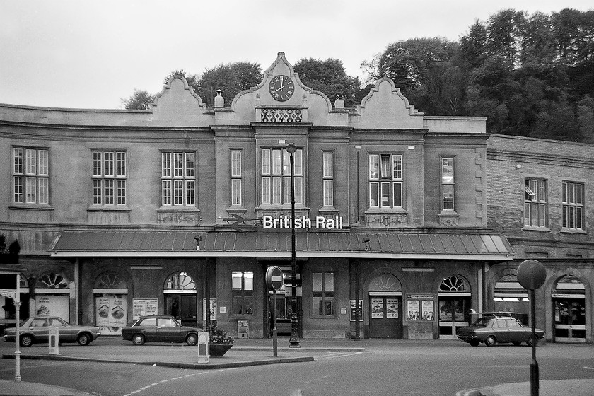 Frontage, Bath Spa station 
 A scene that has changed very little today from when I took this picture in 1979. The frontage at Bath Spa taken at 20.00 reveals a quiet scene with just three cars at the front of the station. To the far left is a Mk. IV Ford Cortina, then a two-door Triumph Toledo and finally, complete with a surf board on the roof a Hillman Hunter. Bath Spa station was built in 1840 for the Great Western Railway by Brunel and is a grade II listed. It is in an asymmetrical Tudor style with curving gables located on the north bank of the River Avon. It was opened on 31 August 1840 and named Bath but was renamed Bath Spa in 1949 to distinguish it from Bath Green Park station, which did not have its name altered from Bath until 1951. 
 Keywords: Frontage Bath Spa station