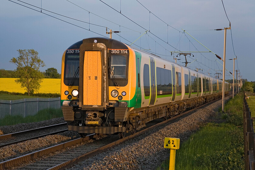 350114 & 350127, LM 19.13 London Euston-Birmingham New Street, Milton Malsor 
 350114 and 350127 approach Northampton passing the village of Milton Malsor working the 19.13 Euston to Birmingham New Street. As can be seen, this location is sixty-two and a half miles from Euston with this train taking just over an hour to reach this point. I like the sycamore (?) tree to the left of the train picked out by the field of fully flowering oilseed rape and the evening sky. 
 Keywords: 350114 350127 19.13 London Euston-Birmingham New Street, Milton Malsor London Midland Desiro