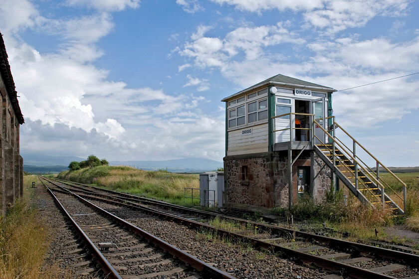 Drigg sIgnal box (Furness, 1871) 
 With a dramatic skyline and the Cumbrian Fells in the background Drigg signal box is seen. The box is a Furness structure dating from 1871 that has been substantially updated utilising UPVC cladding. As well as controlling the level crossing on which I am standing it also operated the crossover seen to the left. This permits freight trains to cross over and then access the sidings into the huge adjacent Low Level Nuclear Waste Repository located between the railway and the sea to my right. 
 Keywords: Drigg sIgnal box Furness 1871