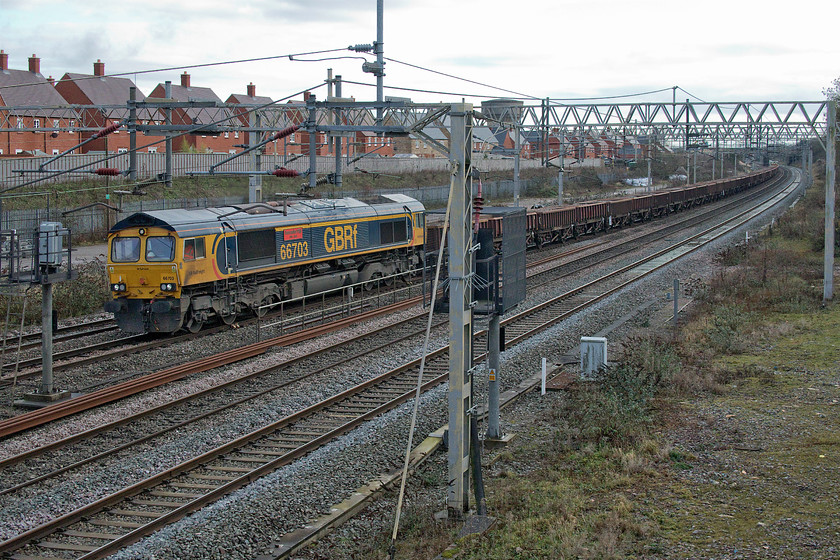 66703, 09.15 Cheddington-Bescot up engineers sidings (7G50, 15E), site of Roade station 
 66703 'Doncaster PSB 1981-2002' hauls a rake of loaded MHA Coalfish wagons past the site of Roade's former station. The train, running as 7G50 09.15 Cheddington to Bescot, was conveying used ballast from a worksite on the fast lines between Bletchley and Tring that involved track replacement. Once back at Bescot, the used ballast is sorted, cleaned and then is ready for reuse again. 
 Keywords: 66703 09.15 Cheddington-Bescot up engineers sidings 7G50 site of Roade station Doncaster PSB 1981-2002 GBRf