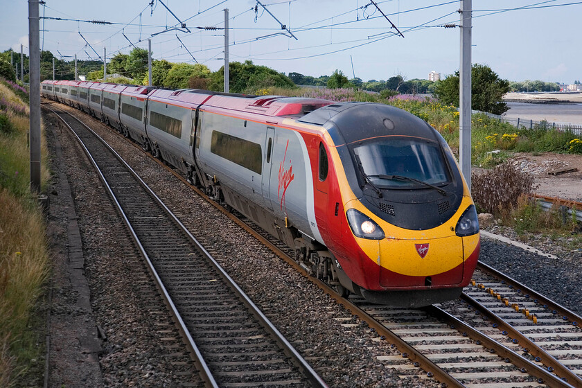 390103, VT 07.30 London Euston-Glasgow Central, Hest Bank level crossing 
 39013 'Virgin Hero' passes Hest Bank at line speed working Vrgin's 07.30 Euston to Glasgow Central service. The buildings and seafront on Morecambes promenade can be seen to the right of the image. 
 Keywords: 390113 07.30 London Euston-Glasgow Central Hest Bank level crossing Virgin Hero