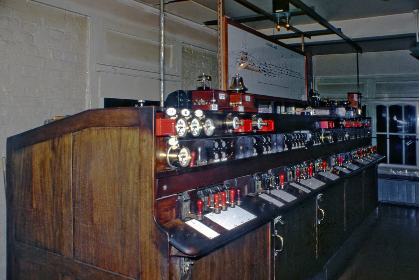 Interior of Salisbury East signal box 
 The signalling around Salisbury (with the exception of the station itself) was converted at the start of the twentieth century by the L&SWR from a conventional mechanical system to an electro-pneumatic set-up. Both Salisbury East (seen here) and Salisbury West signal boxes were purpose-built to accommodate the unusual equipment. Whilst the bells, indicators and plungers were conventional the points and signals were operated by sliding levers. Whilst the down line from Salisbury Tunnel Junction was worked under the conventional absolute block system, the signals between East and West were slotted which allowed block working to be dispensed with. 
 Keywords: Interior of Salisbury East signal box