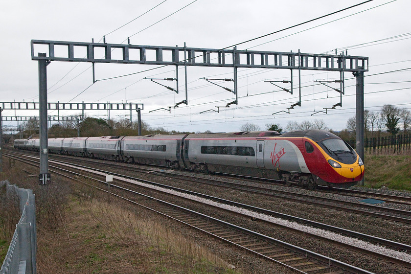 390013, VT 07.20 London Euston-Manchester Piccadilly (1H09, 1E), Ashton Road bridge 
 390013 passes Aston Road bridge between Roade and Hanslope Junction working the 07.20 London Euston to Manchester Piccadilly. The palisade fencing is in evidence here but more careful use of the zoom lens and a change of angle can eliminate most if not all of it from pictures. 
 Keywords: 390013 1H09 Ashton Road bridge