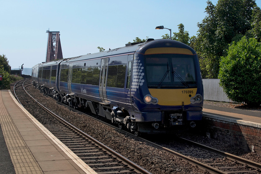 170395, SR 11.02 Edinburgh Waverley-Arbroath (1L61, 4L), North Queensferry station 
 Taken into the light but I wanted the huge structure of the Forth Bridge looming in the background. 170395 arrives at North Queensferry station forming the 1L61 11.02 Edinburgh to Arbroath service. This was a very busy section of line and made one realise what a bottleneck the Forth Bridge is to railway traffic in this area of Scotland. 
 Keywords: 170395 11.02 Edinburgh Waverley-Arbroath 1L61 North Queensferry station