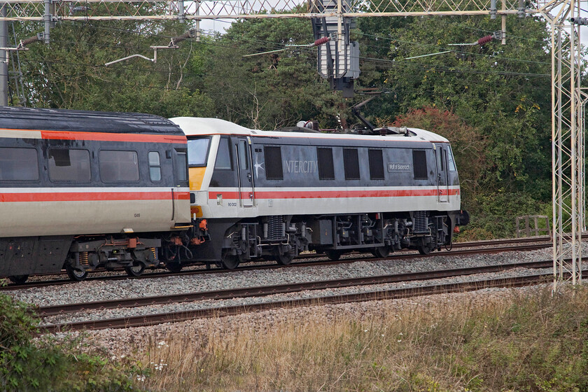 90002, 09.00 Manchester Piccadilly-London Euston (1Z93, 7L), between Roade & Ashton 
 90002 'Wolf of Badenoch' powers the rear of the 1Z93 09.00 Manchester Piccadilly to Euston LSL relief service. The train is seen at speed passing between Roade and Ashton in south Northamptonshire. The reprise of locomotive-hauled trains in a response to the reduction of Avanti services has become the main feature of traffic on the WCML during the early autumn of 2022 that may well remind passengers of the times when these trains were the mainstay of operations on this route. 
 Keywords: Wolf of Badenoch 90002 09.00 Manchester Piccadilly-London Euston 1Z93 between Roade & Ashton