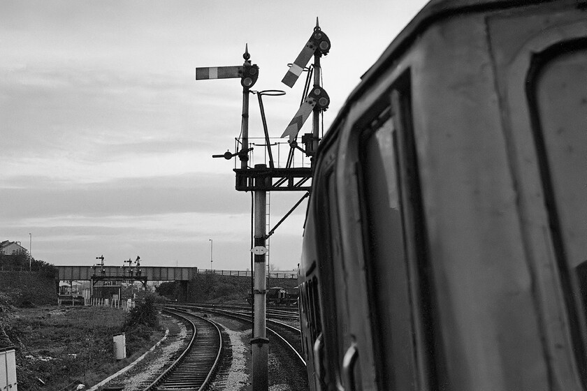 50044, 17.52 London Paddington-Westbury (1K68), Westbury North 
 Having worked hard and fast from London Paddington, leaving at 1752, the 1K68 'Westbury Express' approaches its destination with 50044 'Exeter' leading. Taking the sharply curved and steeply cambered approach to Westbury North both the distant and the home signals have been pulled of permitting access to the station. The rather unassuming flat piece of derelict land to the left is where the Westbury panel box was built some three years after this photograph was taken that precipitated the wiping away of the fine array of mechanical signalling on the lines of this Wiltshire town. 
 Keywords: 50044 17.52 London Paddington-Westbury 1K68 Westbury North Exeter