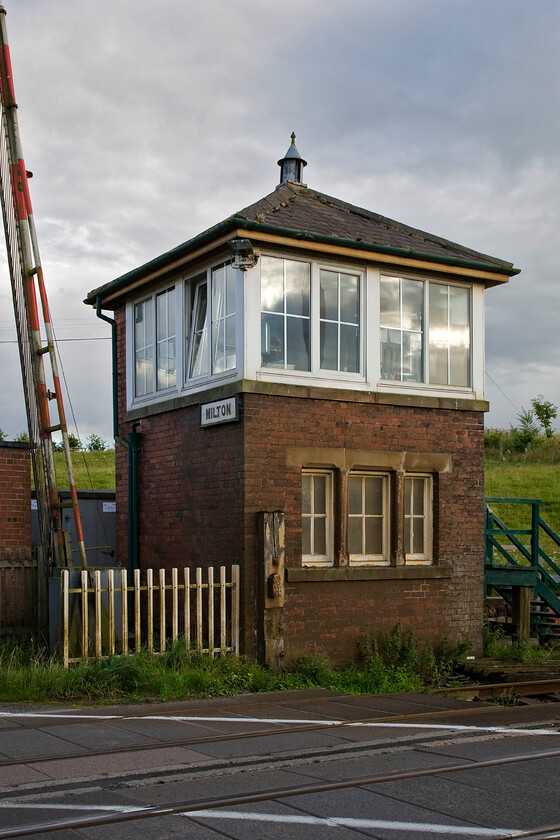 Milton signal box (NE, 1893) 
 Architecturally Milton signal box is superb in its symmetrical dimensions being of North Eastern heritage dating from 1893. It is an intermediate non-block post that controls the level crossing where the very busy A689 crosses the line. Indeed, taking this photograph required some patience and judicious pressure on the shutter due to the number of vehicles passing on the road crossing the tracks! 
 Keywords: Milton signal box North Eastern Railway