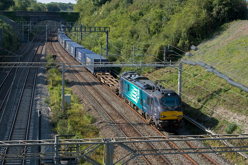 88007, 16.39 DIRFT-Tilbury Container Terminal (4L50, 9L), A508 bridge 
 After a period of time with diesel being used in favour of electric haulage on the southern WCML DRS appears to be reverting back to electric once again. With the 4L48 being electrically hauled recently now it's the turn of the 4L50 16.39 Daventry (DIRFT) to Tilbury with 88007 'Electra' leading for the second day running. The train is seen passing the village of Roade from the former A508 road bridge. 
 Keywords: 88007 16.39 DIRFT-Tilbury Container Terminal 4L50 A508 bridgeElectra