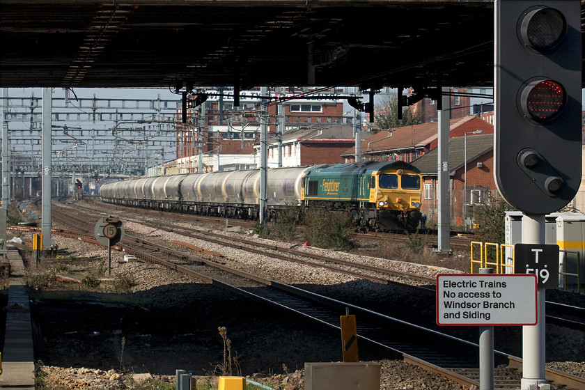 66614, 11.13 Theale-Hope (6M91), Slough station 
 I was particularly pleased to see 66614 '1916 Poppy 2016' leading the 11.13 Theale to Hope cement empties as it was a photographic 'cop'! It is seen about to pass through Slough station in the ridiculously warm February sun that saw people in tee shirts and shorts! I know that it's a bit of a muddled picture but I like that way that the train has been framed by the gloom of the bridge and recently installed T519 colour light. 
 Keywords: 66614 11.13 Theale-Hope 6M91 Slough station