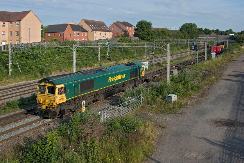 66529, 03.29 Garston-London Gateway (4L52, 2E), site of Roade station 
 The driver of 4L52 will be rubbing his eyes as his train emerges into the bright sunlight after passing through the relative darkness of Roade cutting. 66529 leads the 03.29 Garston to London Gateway past the site of Roade station. 
 Keywords: 66529 03.29 Garston-London Gateway 4L52 site of Roade station Freightliner