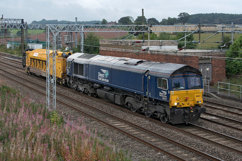 66431, 12.22 Crewe Basford Hall-Bescot Yard (6G94, 32L), Stableford bridge 
 GBRfs 66431 leads the 12.22 Crewe Basford Hall to Bescot Yard infrastructure move past Stableford a few miles south of its starting point. The Class 66 is towing a lone Railcare owned combined Railvac cable handling and cleaning unit. These units are nothing more than a glorified vacuum that sucks up ballast and can, if then required clean it and return it again. This is usually in order to permit staff access to buried cables along the sides of the track. 
 Keywords: 66431, 12.22 Crewe Basford Hall-Bescot Yard 6G94 Stableford bridge DRS Direct Rail Services