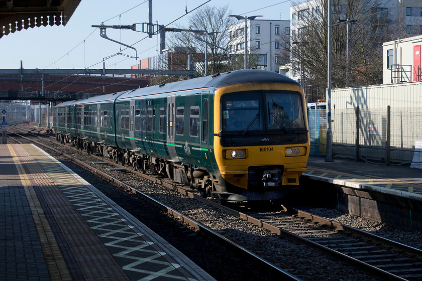 165104, GW 13.35 Bedwyn-London Paddington (1K21, 1L), Slough station 
 165104 speeds through Slough station with he 13.35 Bedwyn to Paddington. I have visited Slough station a number of times, but the amount of development that has been going on in its surroundings is simply staggering! The grand 1884 station is now completely dwarfed, particularly to the north side by hotel developments and the like. 
 Keywords: 165104 13.35 Bedwyn-London Paddington 1K21 Slough station