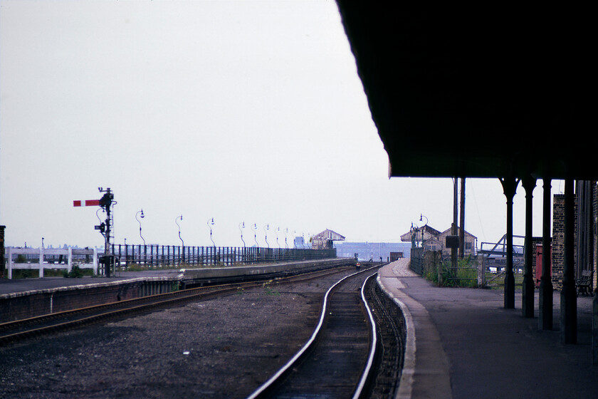 New Holland Pier 
 Using the 135mm telephoto lens attached to my Pentax ME Super camera New Holland pier is seen stretching out into the Humber Estuary. The canopy to the right is that of New Holland Town station that would close exactly a week later along with the railway on the pier and the station at the end. Notice the line of LNER globe lamps to the left that I photographed one of when I visited the pier back in December 1980, see.....https://www.ontheupfast.com/p/21936chg/29820618204/lner-globe-enamel-new-holland-pier The pier is still in use today being technically railway connected and used by a grain and animal feed import/export company with a conveyor belt occupying the route of the right-hand track. 
 Keywords: New Holland Pier