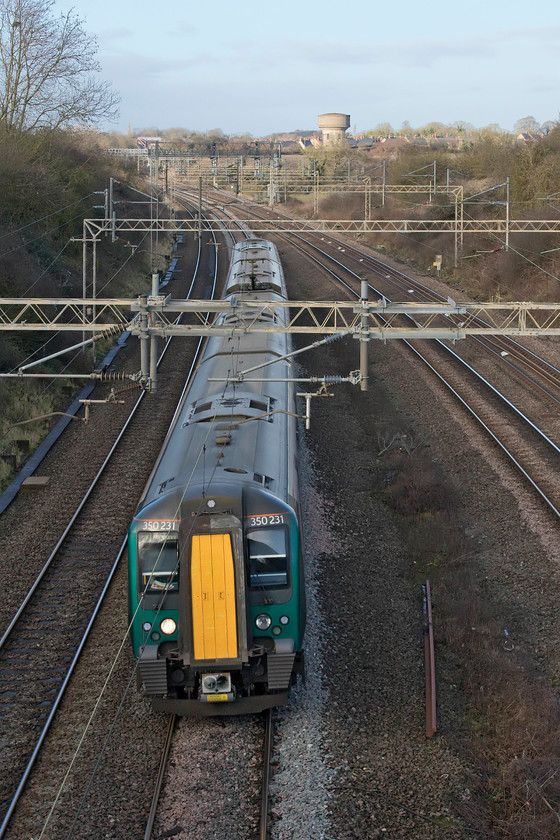 350231, LN 10.33 Crewe-London Euston (1U26, 1L), Victoria station 
 With one of Roade's two water towers in view, currently undergoing conversion into a residence and attracting the attention of Kevin McLoud, 350231 heads south with the 10.33 Crewe to Euston. During weekdays, these London NorthWestern services avoid Northampton taking the Weedon route. However, at the weekends they go via the slower Northampton loop making and an additional stop at the county town. 
 Keywords: 35023110.33 Crewe-London Euston 1U26 Victoria station London Northwestern desiro Roade water tower