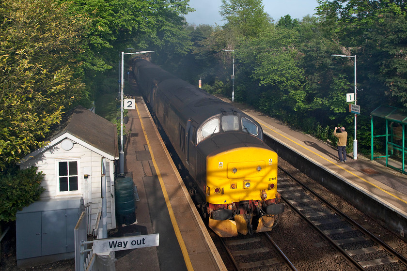 37405 & 37407, LE 17.36 Norwich-Great Yarmouth (2P32, RT), Brundall Gardens station 
 Nearly 4000hp gets the 17.36 Norwich to Great Yarmouth away from Brundall gardens station. With only 3 coaches, this is a ridiculously easy job for these two 50 year old veteran engines, but they still manage to make a lot of noise and plenty of exhaust! Andy can be seen on the other platform videoing the whole scene on his mobile 'phone. 
 Keywords: 37405 37407 2P32 Brundall Gardens station