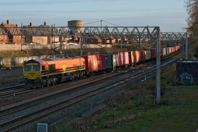 66415, 09.25 Southampton MCT-Garston (4M28, 14E), site of Roade station 
 With the sun getting very low in the sky by this time I was glad that the 4M28 Southampton to Garston Freightliner was being led by 66415 'You Are Never Alone' in its bright new Genesee & Wyoming livery. With the programme to rebrand all of Freightliner's Class 66s underway now more of these orange machines will be seen as time moves on. The train is seen passing the site of Roade's former station. 
 Keywords: 66415 09.25 Southampton MCT-Garston 4M28 site of Roade station You Are Never Alone Genesee & Wyoming