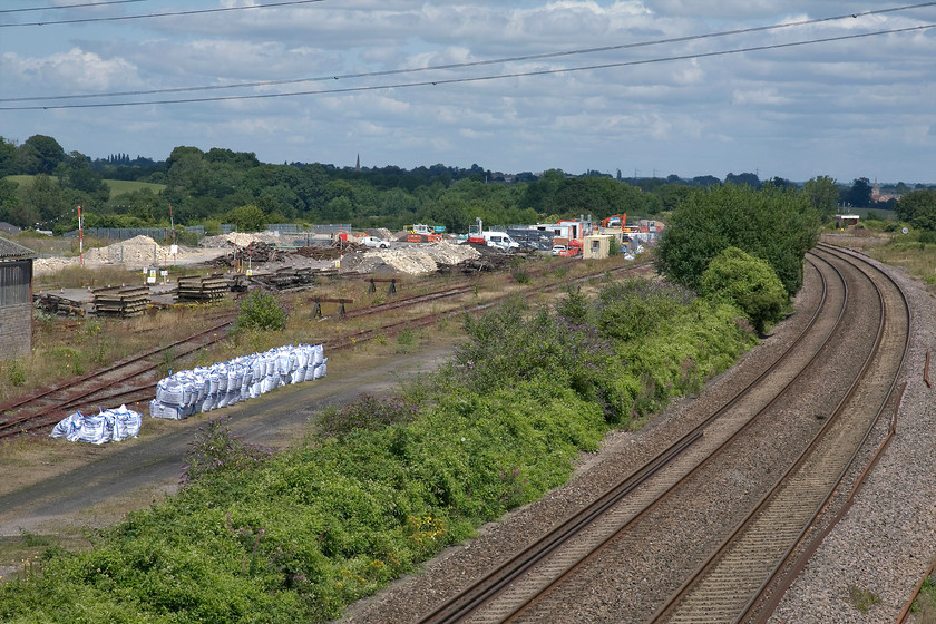 Thingley Junction looking east with associated engineering depot 
 The only signs of the pending electrification at Thingley Junction is the building of the encampment of composed of the various contractors who have arrived on site. Soon the posts for the wiring will be installed and this view of the GWML looking east towards Chippenham will be far less open than it is now. The spire of Chippenham's St. Paul's church can be seen rising above the trees on the skyline 
 Keywords: Thingley Junction looking east with associated engineering depot Chippenham Bath Melksham Westbury