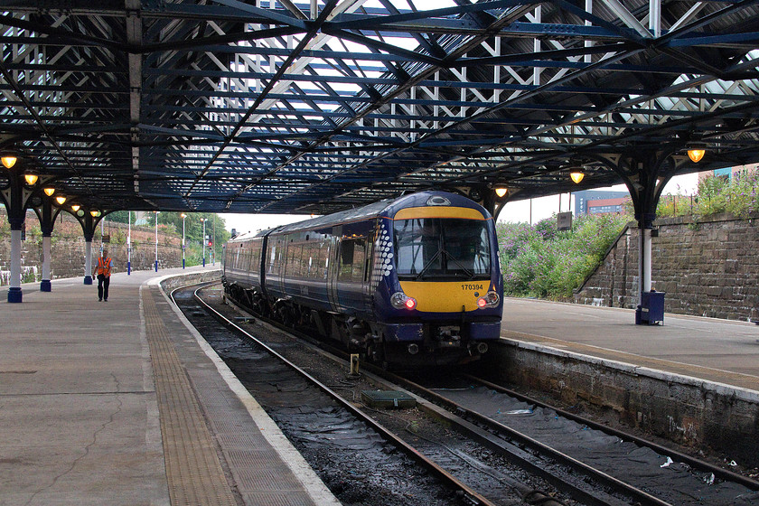 170394, SR 19.36 Dundee-Perth ECS (5L34), Dundee station 
 170394 leaves one of Dundee's west-facing bay platforms with the 19.36 ECS working to Perth. Despite the complete re-building of Dundee station, this magnificent glazed wrought iron roof remains having had a thorough clean and repainting. Also, notice the traditional looking lighting that is far more in keeping than many other types that could have been installed. 
 Keywords: 170394, SR 19.36 Dundee-Perth ECS 5L34 Dundee station