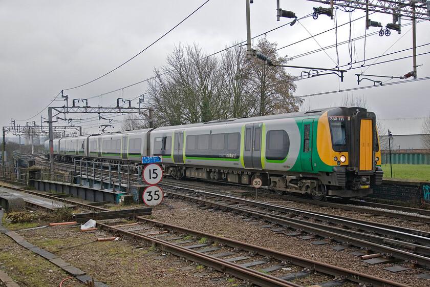 350111, LM 07.54 London Euston-Birmingham New Street, Northampton station car park 
 It's just gone 09.00 as 350111 arrives at Northhampton, seen from the station's car park, working the 07.54 Euston to Birmingham New Street. The line heading off to the left once led to Bridge Street station to then continue eastwards to Wellingborough, Bedford and beyond. It also led to Northampton's steam shed (4B) leading to the alternative route joining the Weedon 'old' line at Blisworth. 
 Keywords: 350111 07.54 London Euston-Birmingham New Street Northampton station car park London Midland Desiro