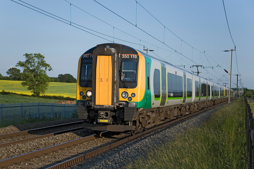 350119, LM 18.29 London Euston-Birmingham New Street (1G40), Milton Malsor SP740553 
 Even a humble unit can look nice in the right weather conditions! 350119 leads another Desiro past Milton Malsor near to Northampton working the 1G40 Euston to New Street service. I stood on my ladder in a very similar position a week or two past with the comparison between the oil seed rape field in the background being the most noticeable change, see.... https://www.ontheupfast.com/p/21936chg/30059321565/x350114-350127-19-13-london-euston 
 Keywords: 350119 18.29 London Euston-Birmingham New Street 1G40 Milton Malsor SP740553 London Midland Desiro