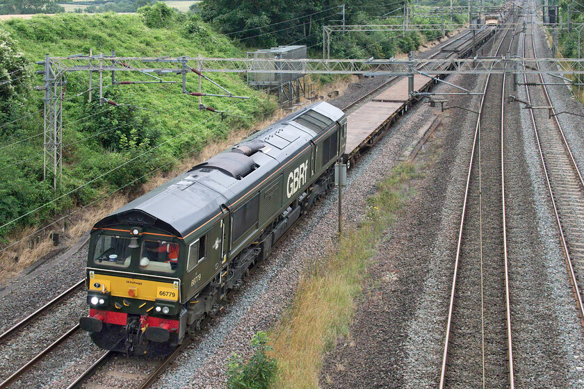 66779, 10.15 Willesden West London Junction-Bescot (6G51, 2L), Victoria bridge 
 After a week of brilliant sunshine with associated hot temperatures, the weekend has proved to be grey and dull; not the best weather in which to photograph a Class 66 in this retro livery! 66779 'Evening Star' leads the 10.15 Willesden West London Junction to Bescot returning engineering train. It is leading a number of flats some of which are carrying some used track panels along with some HQAD bogie autoballaster wagons towards the rear. The train is seen passing Victoria bridge just south of Roade in Northamptonshire. 
 Keywords: 66779 10.15 Willesden West London Junction-Bescot 6G51 Victoria bridge Evening Star