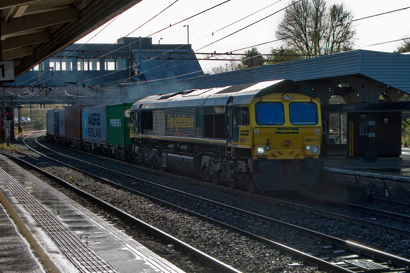 66571, 07.39 Felixstowe North-Lawley Street (4M96), Northampton station 
 Taken totally against the winter light, 66571 brings the 07.39 Felixstowe to Lawley Street Freightliner through Northampton station. Breaking the photographic conventions sometimes pays an unexpected dividend such as the lovely light reflecting off the wet platform in the foreground. 
 Keywords: 66571 07.39 Felixstowe North-Lawley Street Northampton station Freightliner 4M96