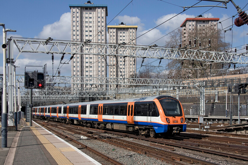 710307, LO 13.00 London Euston-Watford Junction (2D79, 1L), London Euston station 
 I wonder if anybody has ever approached the residents of the tower blocks regarding the installation of a RailCam? In this view at Euston, London Overground's 710307 departs with the 2D79 13.00 local stopper to Watford Junction. Along with September, I find the lighting in early spring when the sun is out the best for photography with a sparkling quality to it as seen in this image 
 Keywords: 710307 13.00 London Euston-Watford Junction 2D79 London Euston station London Overground