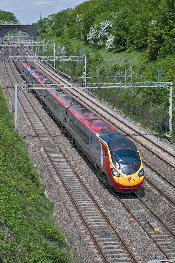 Class 390, VT 10.58 Preston-London Euston, Hyde Road bridge 
 An unidentified Class 390 Pendolino works through Roade seen from the village's Hyde Road bridge working the 10.58 Preston to Euston service. It was nice to be standing on the bridge with the warm early summer sun on my back. 
 Keywords: Class 390 10.58 Preston-London Euston, Hyde Road bridge Virgin West Coast Pendolino