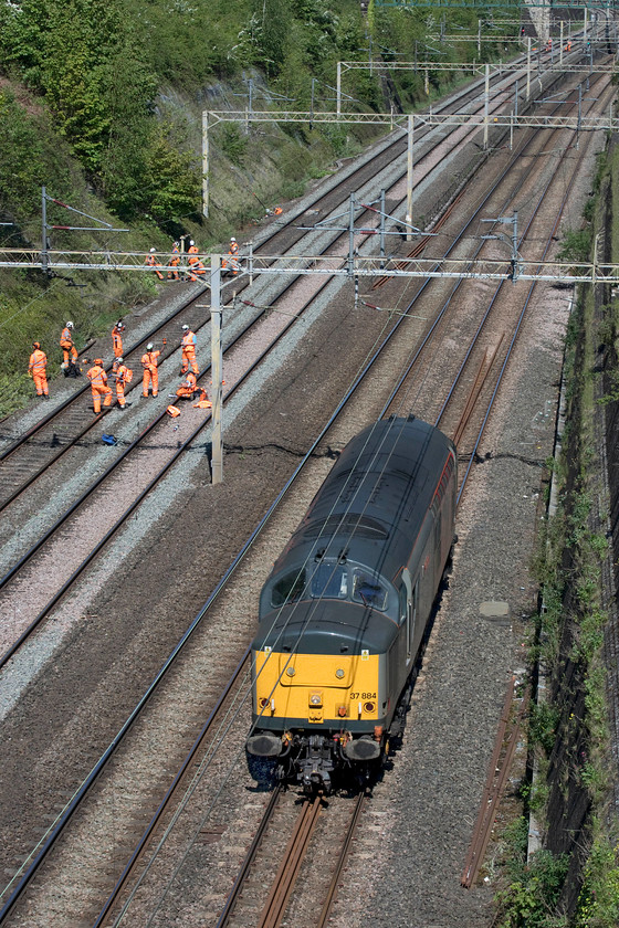 37884, 10.08 Leicester LIP-Clacton CSD (0E98, 20E), Roade cutting 
 Rail Operations Group 37884 'Cepheus' trundles light engine through Roade cutting passing a group of ever resting track workers as the 10.08 Leicester to Clacton 0E98. After collecting a unit at the Essex depot it will then travel overnight to Kilmarnock. 
 Keywords: 37884 10.08 Leicester LIP-Clacton CSD 0E98 Roade cutting Rail Operations Group ROG