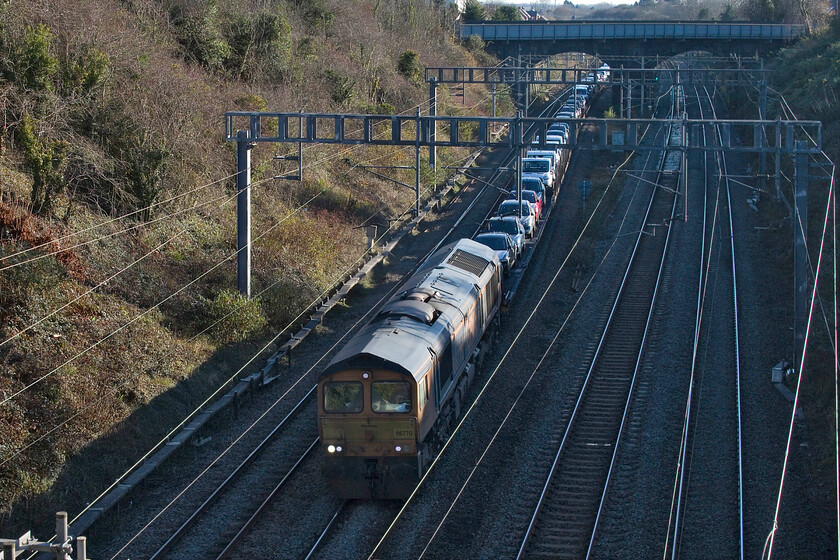 66770, 09.28 Dagenham Docks-Garston (6X43, 25E), Hyde Road bridge 
 Even by lunchtime with three weeks until the shortest day, the sun is not high enough in the sky to illuminate the depths of Roade Cutting. 66770 leads the 6X43 Ford car train under Roade's Hyde Road bridge taking all manner of cars and vans north from Dagenham, where they are imported from Europe, to their distribution centre at Garston. 
 Keywords: 66770 09.28 Dagenham Docks-Garston 6X43 Hyde Road bridge GBRf