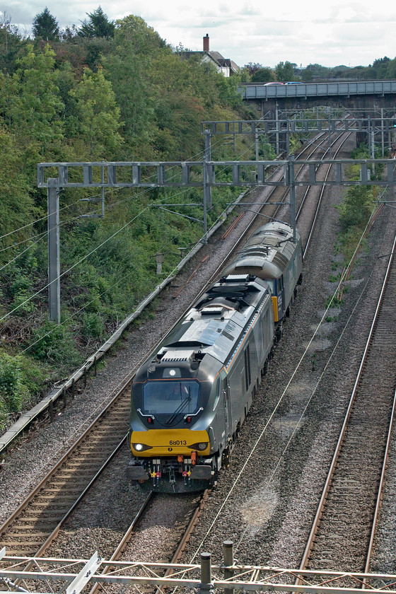 68013 & 57002, 09.35 Wembley TMD-Crewe Gresty Bridge (0K69, 29E), Hyde Road bridge 
 There are regular moves between Crewe Gresty Bridge and Wembley every Saturday in both directions. This is so that the Chiltern Railways Class 68s, that are operated on its behalf by DRS, can be serviced and receive their exams. Other locomotives are often dragged as part of these workings but a Class 57 is not particularly common. 68013 collected 57002 'Rail Express' en route at Willesden after the Class 68 had done a rather convoluted move after it set off earlier in the morning that wiped off its fifty-seven minute early departure. The duo is seen passing through Roade from the village's Hyde Road bridge. 
 Keywords: 68013 57002 09.35 Wembley TMD-Crewe Gresty Bridge 0K69 Hyde Road bridge Rail Express