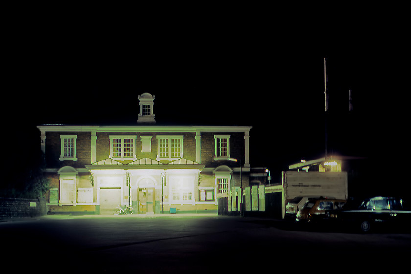 Frontage, Market Harborough station 
 The grand frontage of Market Harborough station is seen at night taken as a time exposure utilising Graham's Velbon tripod. The station is Grade II listed and is the second station constructed in 1884 replacing the far simpler LNWR station built in 1850. The building was constructed by Parnell and Sons of Rugby designed by the esteemed architect John Livock. It cannot be seen clearly in this photograph but the building sits within a triangle of lines somewhat hemmed in as both are elevated. The line to the right is the Midland line to and from St. Pancras with the former line to the left being the now closed LNWR cross-country route to Northampton. At the time of our visit in 1980, this line was still open and in sporadic use for freight. It would take another forty one years before I would stand in a similar spot to this and take a daylight photograph of this fine structure, see..... https://www.ontheupfast.com/p/21936chg/30017882627/x5-frontage-market-harborough-station 
 Keywords: Frontage Market Harborough station LNWR Midland Railway