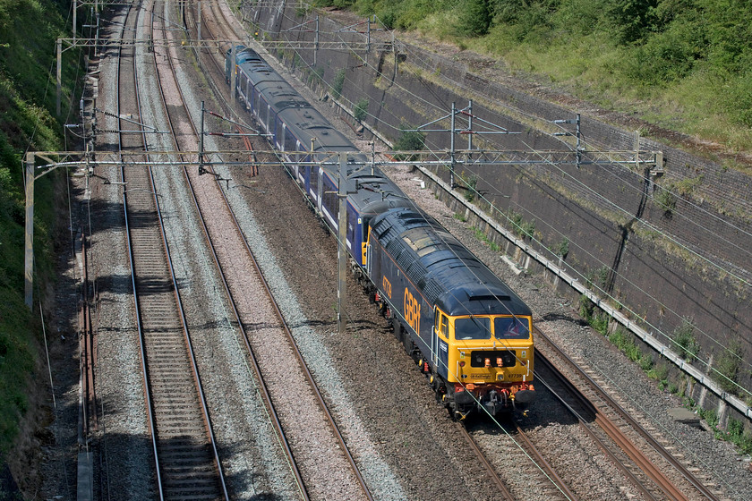 47739, 360107 & 47749, 12.15 Ilford EMUD-Northampton EMD (5Q36, 14L), Roade cutting 
 A combo of blueness passes through Roade cutting almost reminiscent of BR's corporate image days if not for the slight variance in the shading. Out of sight, on the front, 47749 'City of Truro' leads 360107 with 47739 coming along for the ride at the rear. The train was passing slowly through Roade cutting as the 5Q36 12.15 Ilford to Northampton conveying the former GA Desiro for temporary storage and one hundred and ten miles an hour modification at the Siemens' depot at Kingsheath. The unit will eventually be repainted and branded as EMR for use on the Corby to St. Pancras services whenever the newly electrified route is energised, tested and cleared for use. 
 Keywords: 47749 360107 47739 12.15 Ilford EMUD-Northampton EMD 5Q36 Roade cutting GA Desiro GNRf City of Truro