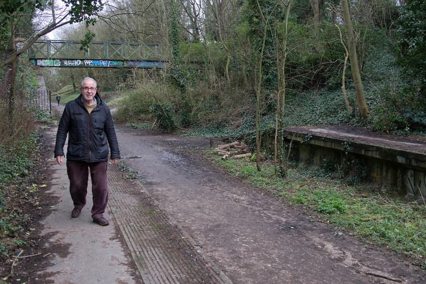 Andy, Parkland Walk, former Crouch End station 
 Andy walks along the former eastbound platform at Crouch End. The station was opened in 1867 by the Great Northern. It led a quiet life undergoing a rebuild in 1952 but was closed a mere two years later to passengers in 1954. The lines remained in use for freight and stock movements until complete closure came in the early 1970s due to the condition of a bridge and of the flyover crossing the ECML at the far eastern end. The tracks were lifted in 1972 and most infrastructure removed. 
 Keywords: Andy Parkland Walk former Crouch End station