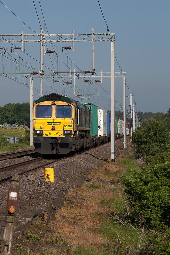 66589, 04.57 Trafford Park-Felixstowe North (4L97), Wilson s Crossing 
 66589 drifts downhill gently into Northampton past Wilson's Crossing leading the heavily laden 04.57 Trafford Park to Felixstowe North (4L97) Freightliner. To take this picture, a ladder is essential and the selection of portrait mode is also pretty important due to conspicuous 'clutter'. 
 Keywords: 66589 4L97 Wilson's Crossing