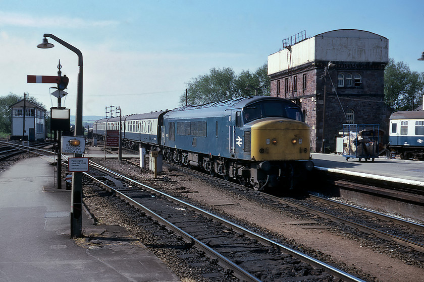 46034, 09.18 Paignton-Derby, Exeter St. Davids station 
 A classic scene at the western end of Exeter St. David's sees 46034 arriving at the head of the 09.18 Paignton to Derby service. Apart from the West signal box to the left, the photograph is dominated by the former GWR water tower in the background. This was converted from one of Brunel's pumping houses used to power the flawed and ultimately ill-fated atmospheric railway. Quite how it was permitted to be knocked down to make way for the Exeter panel box in 1984 is absolutely beyond me. I can console myself that the likelihood of this happening today would be nil! 
 Keywords: 46034 09.18 Paignton-Derby Exeter St. David's station