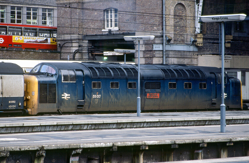 55017, 12.34 Hull-London King's Cross (1A18), London King's Cross station 
 A second view of one of my personal favourite Deltics, 55017 'The Durham Light Infantry', as it enters King's Cross station. It has just brought the 1A18 12.34 ex-Hull from East Yorkshire and is looking just a little work stained with dirty and faded blue paintwork. Like the majority of its twenty-two classmates, this was the last year of Deltic operation with this example lasting until 31.12.80. Notice the 63 bus on York Way proudly displaying its Bartex sunglasses advertising. This very stylish brand of chromatic apparel was very much at the 'quality' end of the market but search as I have, I cannot find out what happened to the company. A photograph taken from a very similar position as this was taken on a visit to King's Cross in 2018, see.... https://www.ontheupfast.com/p/21936chg/23772626004/x91113-1s18-43295-1s16-london-king. 
 Keywords: 55017, 12.34 Hull-London King's Cross (1A18), London King's Cross station The Durham Light Infantry