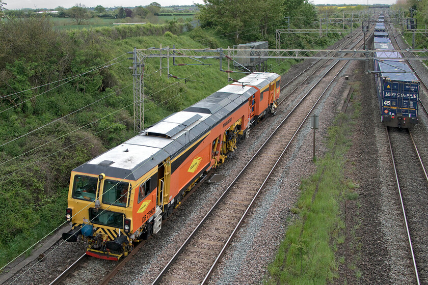 DR73929, ballasting & 10.51 DIRFT-Ripple Lane (4L98, RT), Victoria bridge 
 As the diverted 10.51 Daventry to Ripple Lane 'Tesco Express' heads south on the up fast the cause of the diversion is in view. Colas tamper DR73929 goes about its work re-ballasting the up slow line. During the is process it makes painfully slow progress along the track at what is considerably less than walking pace and making a fair bit of noise as it does so! The photograph is taken from Victoria bridge located just south of Roade in Northamptonshire. 
 Keywords: DR73929 ballasting 10.51 DIRFT-Ripple Lane 4L98 Victoria bridge Colas Tesco Express