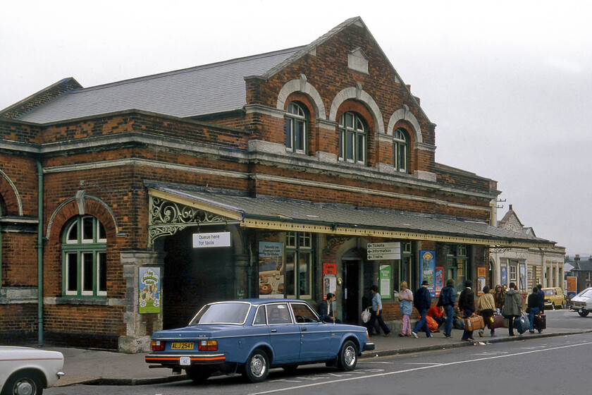 Frontage, Salisbury station 
 A busy Saturday afternoon scene outside the font of Salisbury station. The early history of railways in Salisbury is a complicated one that deserves a book in its own right and is a story that would document the long battle between the L&SWR and the GWR. The lighter 'grey bricked' building to the rear seen here back in 1981 (dated nicely by the cars) was built in 1859 and designed by Sir William Tite for the Salisbury and Yeovil Railway Company (soon to become the L&SWR) simply as an extension to their existing station. However, over time other operations by them and the GWR alike closed and amalgamated with it extended again in 1902 and that is the red brick structure seen here complete with its canopy. Whilst Historic England has designated what is seen here as Grade II it is the frontage of the older structure seen to the extreme right, that is of greater interest according to their citation. Whilst the building still stands and is very much in use today, the blue Volvo taxi has long gone last being on the road in 1991! 
 Keywords: Frontage Salisbury station