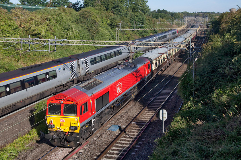 66135, outward leg of The Walsall Concerto, 07.27 London Euston-Birch Coppice Exchange Sidings (1Z33) & class 221, VT 07.17 Chester-London Euston (1A72, 1E), Victoria Bridge 
 Looking resplendent in it smart DB red livery 66135 brings up the rear of The Walsall Concerto railtour. This railtour was a trip around the rare track of the West Midlands that went as far south as Worcester before returning back down the WCML later in the evening. The Voyager was working the 07.17 Chester to Euston. The whole scene is captured at Victoria Bridge just south of Roade on the WCML. 
 Keywords: 66135 The Walsall Concerto, 07.27 London Euston-Birch Coppice Exchange Sidings 1Z33 class 221 1A72 Victoria Bridge