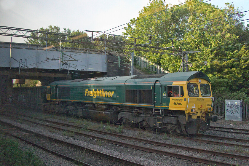 66606, 19.56 Northampton Castle Yard-Tunstead Sidings (6Z99, RT) Northampton Spencer Road bridge 
 A pretty awful picture taken from a moving train but the subject is interesting so worthy of inclusion for a couple of reasons. Firstly, I have never managed any photographs of the evening Northampton Castle Yard to Tunstead empty stone wagons due to its inconvenient timings and that it heads north away from Northampton away from my home location. The second reason is that 66606 is a photographic cop; my second of the day. The Class 66 is seen slowly reversing the stock away from Castle Yard under Northampton's Spencer Road bridge. The locomotive will then run round the stock and head off north back to Derbyshire. 
 Keywords: 66606 19.56 Northampton Castle Yard-Tunstead Sidings 6Z99 Northampton Spencer Road bridge Freightliner