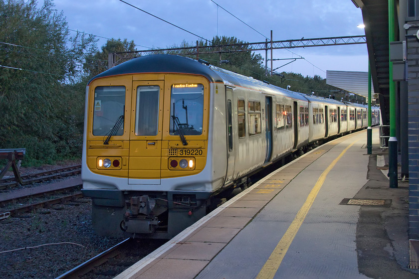 319220, LN 06.51 Northampton-London Euston (2N10, 3L), Northampton station 
 In the half-light at Northampton station, 319220 leads two other classmates forming the 06.51 to London Euston. London Northwestern have fifteen class 319 from three subsets that are used on morning and evening commuter services. However, they are due for replacement soon so could end up moving north to join the others already in service with Northern or be converted for bi-mode use marketed as 319 Flex units. Notice that this particular unit is totally unbranded perhaps indicating that it could be an early candidate to go off-lease. 
 Keywords: 319220 06.51 Northampton-London Euston 2N10 Northampton station