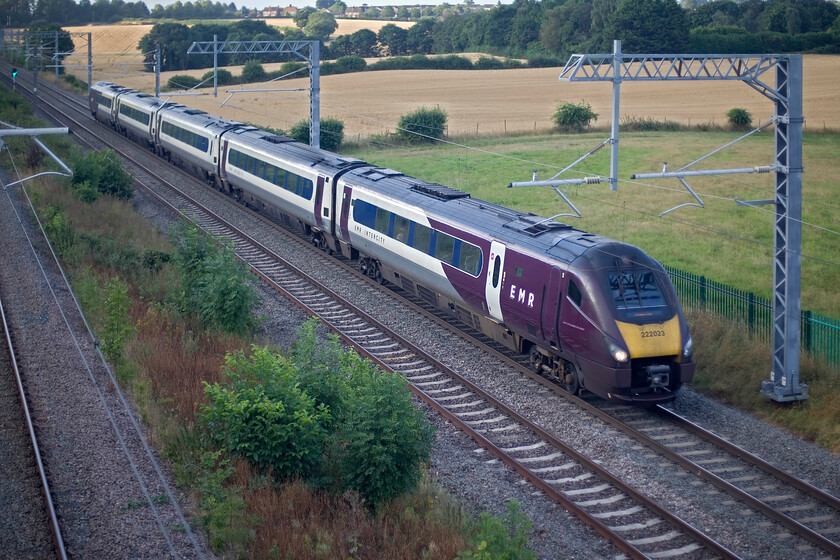 222023, EM 06.05 London St. Pancras-Nottingham (1D06, 1L), Irchester SP927667 
 In rather flat early morning light 222023 descends that last section of Sharnbrook Bank working the 06.06 St. Pancras to Nottingham service. Despite the cloudy conditions tarnishing the image somewhat, the rising sun can be seen illuminating the village of Irchester in the background. 
 Keywords: 222023 06.05 London St. Pancras-Nottingham 1D06 Irchester SP927667 EMR Meridian